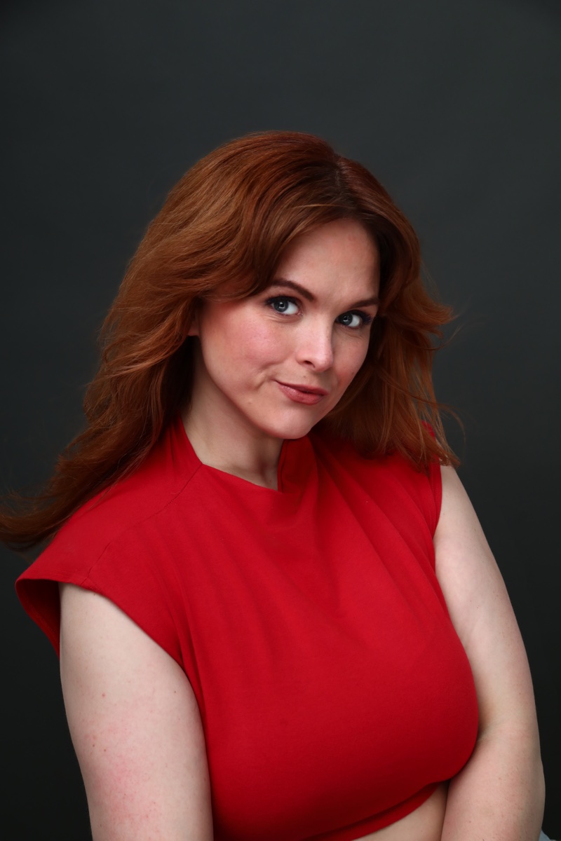 Blaire Erskine giving the camera a sly look in a red top.